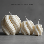 Three swirl sculptural pillar candles on a gray background