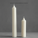 Two white striped candles on a gray surface with a dark gray background