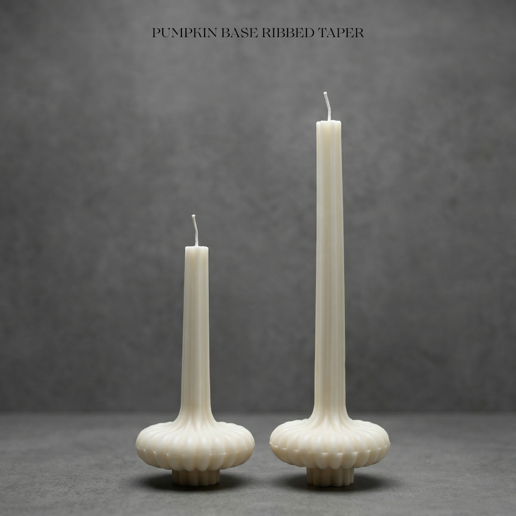 Two ribbed taper candles on pumpkin bases against a gray background
