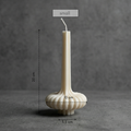 White candle with decorative base on a gray background, showing measurements.