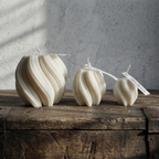 Three decorative candles on a wooden surface with a gray textured background