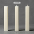 Three white candles of different heights on a gray background with measurements.