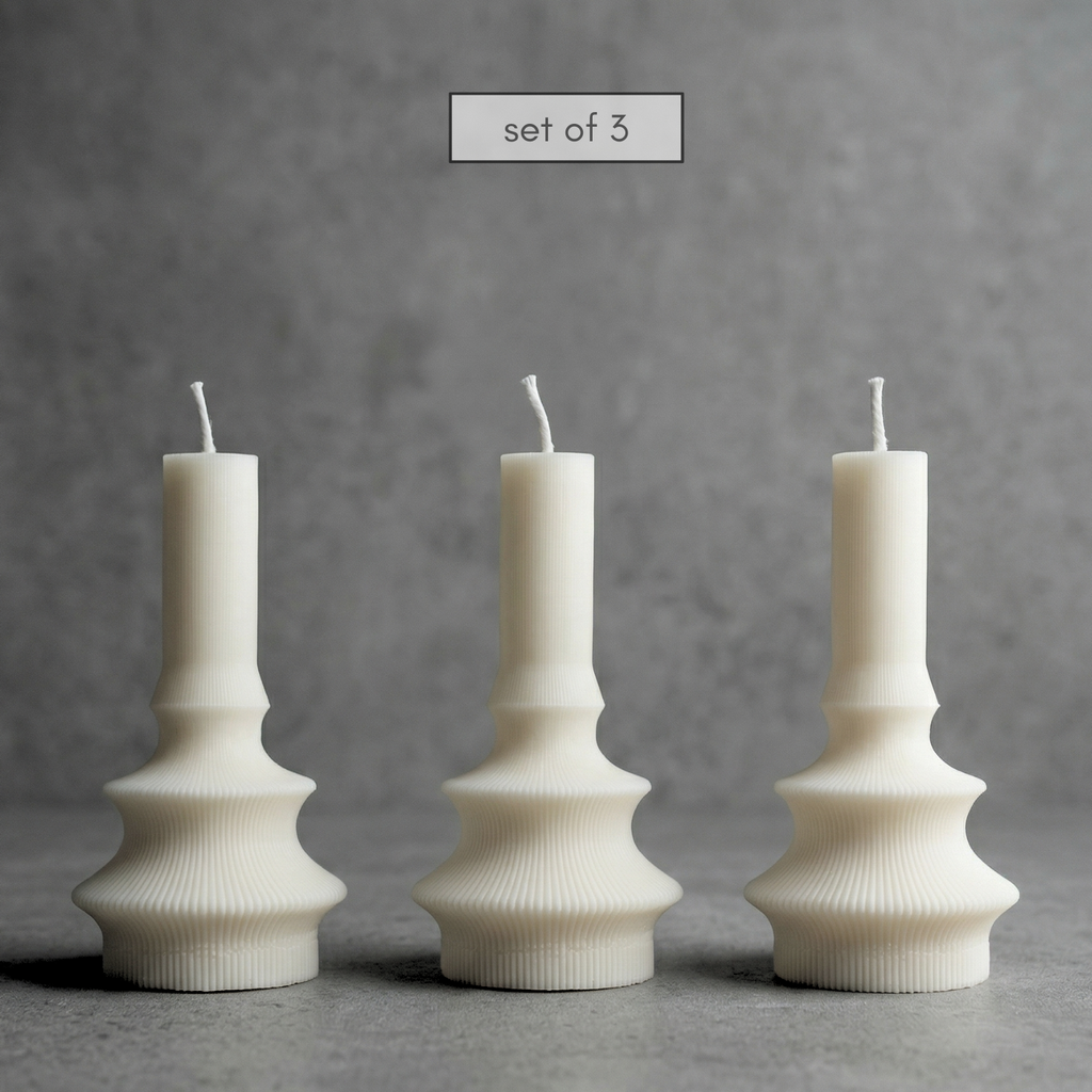 Set of three white textured candles on a gray background