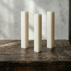 Three white candles on a wooden surface with a gray background