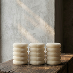 Three ribbed candle holders on a wooden surface with a textured wall background
