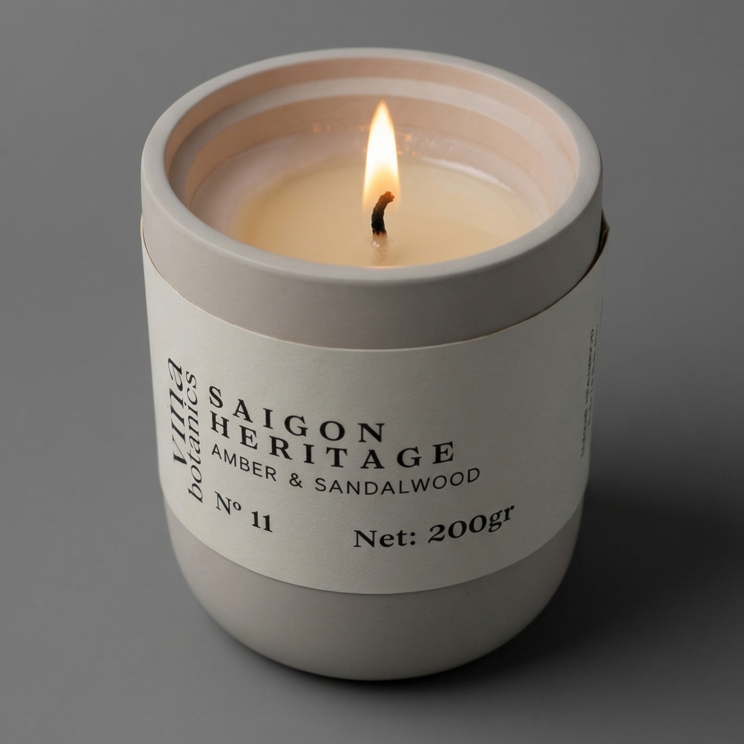 Candle in a white container labeled 'Saigon Heritage' on a gray background