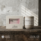 Vina Botanics candle and packaging on a wooden surface with a neutral background