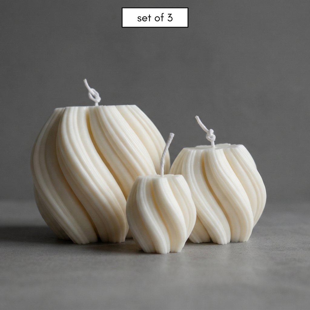 Set of three white textured candles on a gray background
