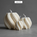 Set of three white textured candles on a gray background