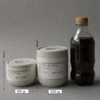Two containers labeled 'Afternoon Royal Tea in Hue' with measurements and a bottle of dark liquid on a gray background.