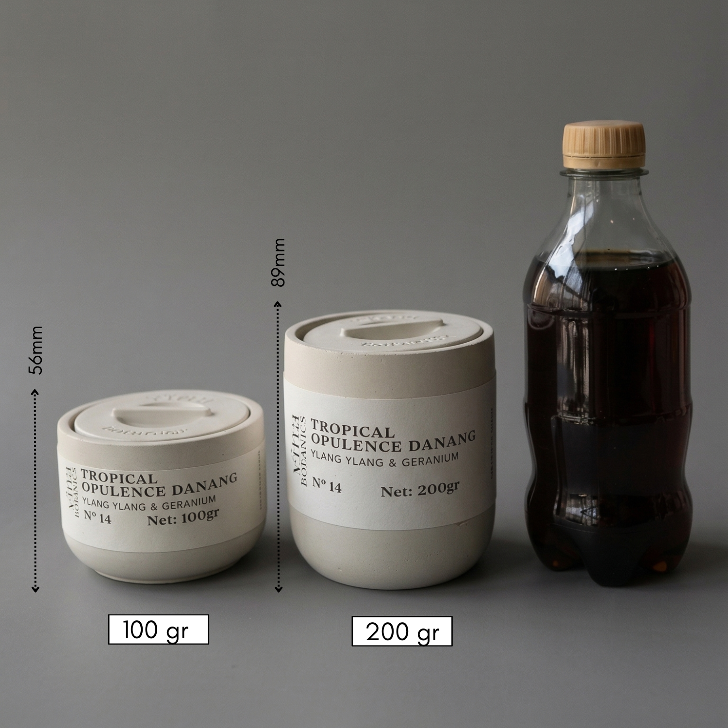 Two containers labeled 'Tropical Opulence Danang' with measurements and weights, next to a bottle on a gray background.